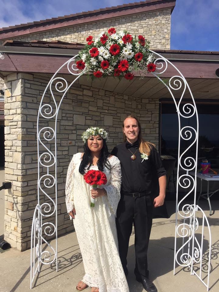 Couple beneath red and white wedding arch